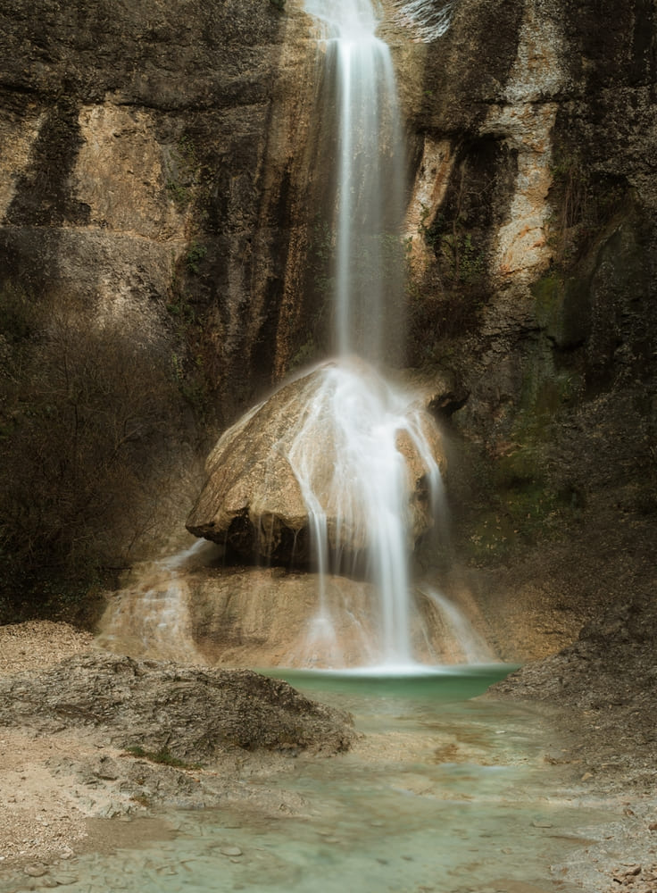 Photographie d'une cascade en pose longue avec des rochers calcaires et une eau verte turquoise