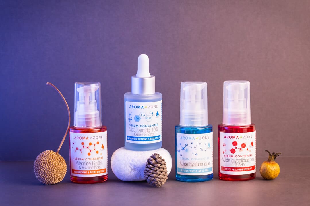 Photographie de produits avec des éléments naturels sur un fond dégradé du violet à l'orangé