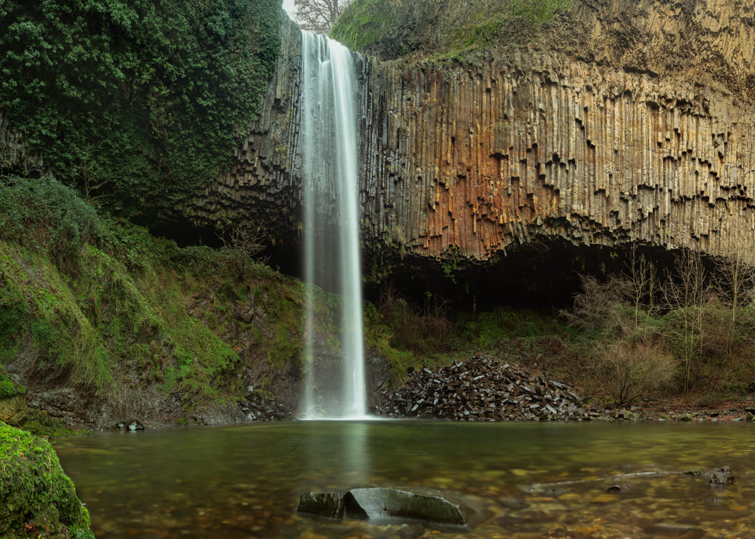 Photographie paysage d'une cascade et d'orgues basaltiques en Ardèche  en hiver avec des couleurs vertes et rouilles