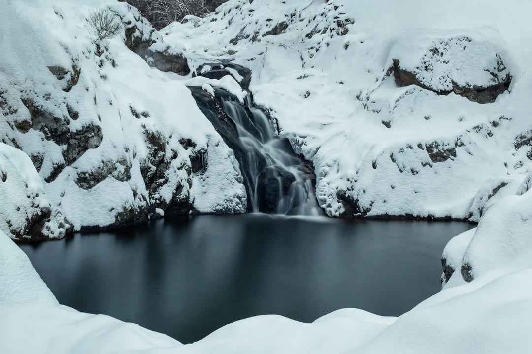 Photographie d'une rivière enneigée avec une pose longue sur l'eau